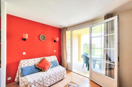 - un salon avec un canapé et un mur rouge dans l'établissement La résidence du Lac - maeva Home - Appartement 2 pièces 4 personnes - Sélection MAE-5911, à Monflanquin