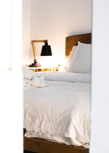 a bedroom with a bed with white sheets and a lamp at ESO Santa Teresa in Santa Teresa Beach
