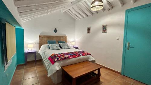 a bedroom with a large bed and a wooden table at La Casa de los Colores in Olvera