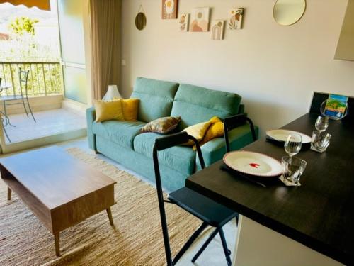 un salon avec un canapé bleu et une table dans l'établissement Studio La Napoule 2 min beach 4 people air conditioning, à Mandelieu-la-Napoule