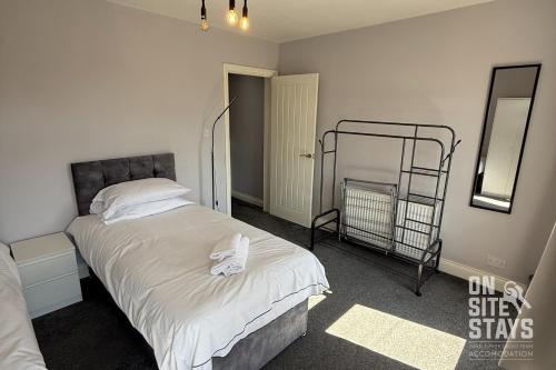 Un dormitorio con una cama con sábanas blancas y un espejo. en OnSiteStays - 4 bedroom house with 2 bathrooms, en Welling