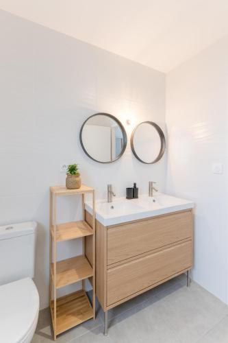 La salle de bains est pourvue d'un lavabo, de toilettes et de miroirs. dans l'établissement MENEZ BIAN - Maison de plein pied tout confort, à Saint-Pabu