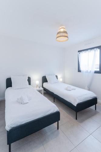 deux lits dans une chambre aux murs blancs dans l'établissement MENEZ BIAN - Maison de plein pied tout confort, à Saint-Pabu