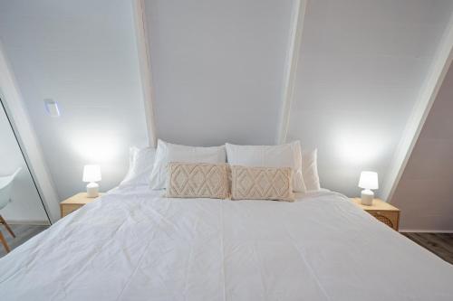 a white bed with two lamps on two tables at Casa Clara Monteverde in Puntarenas