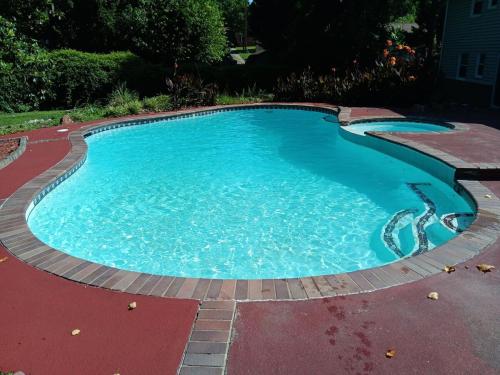 a large swimming pool with blue water in a yard at Theater, heated pool and hot tub near HPU and Furniture Market in Jamestown