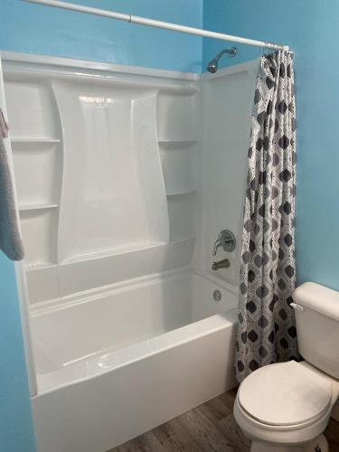 a bathroom with a white tub and a toilet at Theater, heated pool and hot tub near HPU and Furniture Market in Jamestown