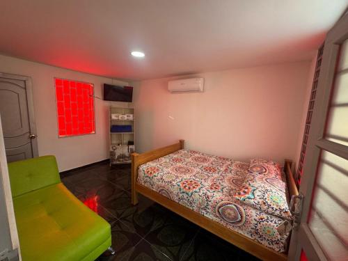 a small bedroom with a bed and a green chair at Hotel Centro vacacional El Cielo in Rivera