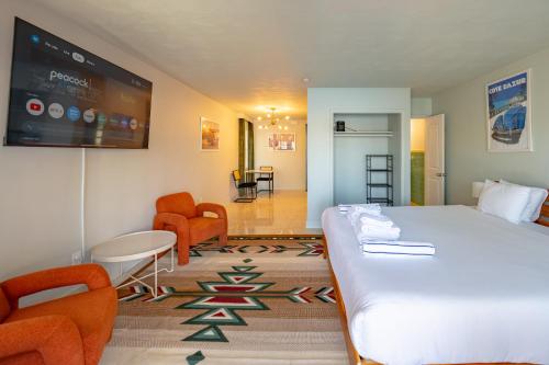a bedroom with a bed and chairs and a tv at Tropical Breeze in Clearwater Beach