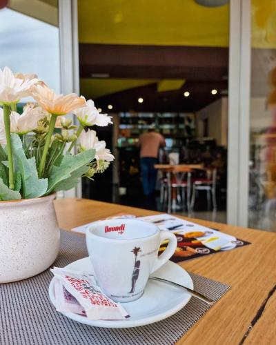 a cup of coffee sitting on a table with flowers at Hotel Brkić Sarajevo Airport - Free Parking in Sarajevo