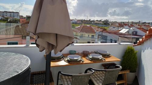 an umbrella on a balcony with a table and chairs at Relax & Travel in Almada