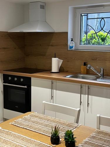 une cuisine avec une table, un évier et une cuisinière dans l'établissement Ambiance cocooning pour visiter la Normandie, à Giberville