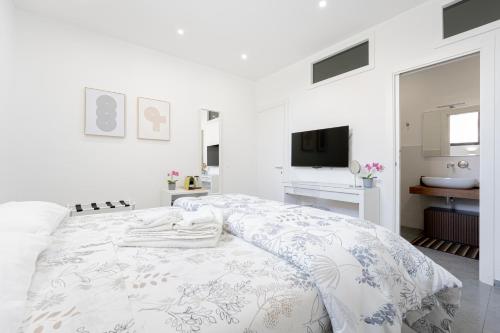 a white bedroom with a bed and a television at Eos - Elegants Apartments & Suites in Siracusa