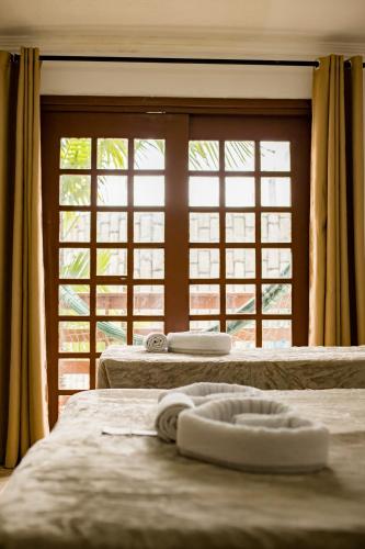 two beds in a room with a large window at Estação do Sol Praia Hotel in Porto De Galinhas