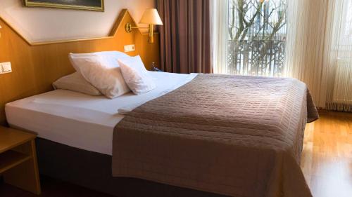 a large bed in a hotel room with a window at Komfort Hotel Am Kurpark in Bad Homburg vor der Höhe