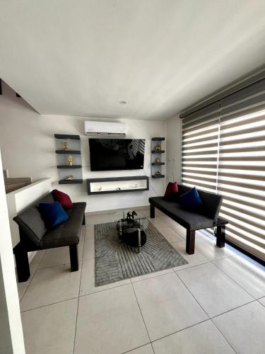 a living room with two chairs and a flat screen tv at Comodidad con Alberca y Seguridad cerca de Galerías in Mazatlán