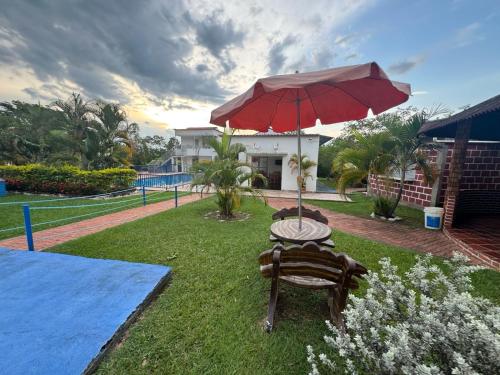 a patio with a table and a red umbrella at Hotel Centro vacacional El Cielo in Rivera