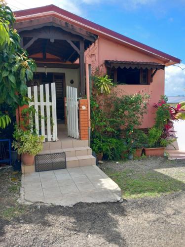 a small pink house with a white door and stairs at Pomme Cannelle in Le Lamentin