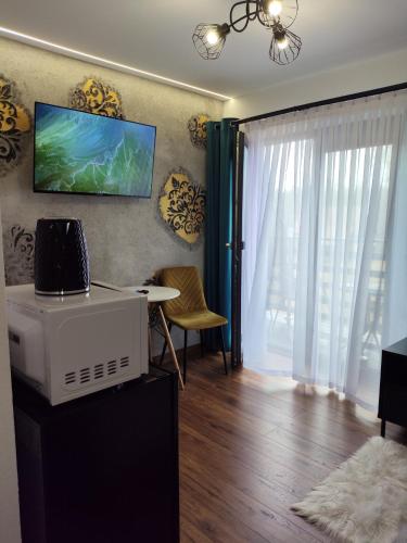 a living room with a table and a television on the wall at Noclegi SKORUSINKA in Witów