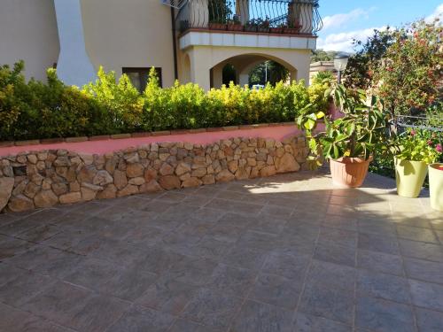 a stone wall next to a house with potted plants at Appartamenti La Collina in Jerzu
