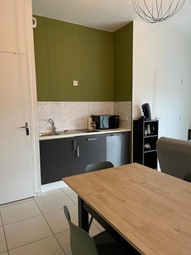 - une cuisine avec des murs verts et une table avec des chaises dans l'établissement Zenith St Étienne Appartement, à Saint-Étienne