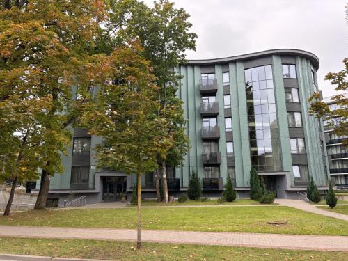 a green building with a tree in front of it at Ballare House in Druskininkai