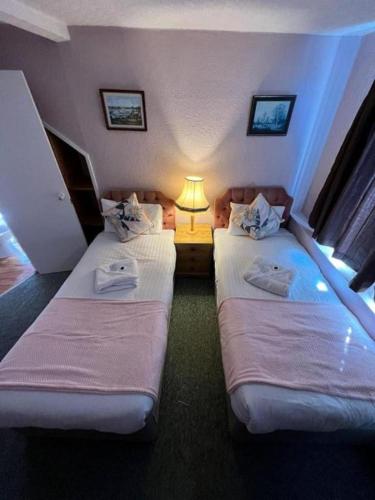 two beds in a hotel room with a lamp at Belvedere Guest House, Great Yarmouth in Great Yarmouth