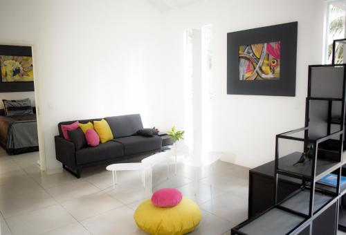 a living room with a couch and a yellow stool at Casa Bromélia in Palmeiras