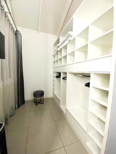a walk in closet with white shelves and a black stool at Casa Bromélia in Palmeiras