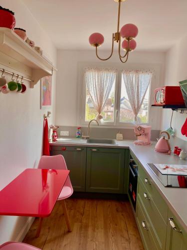 une cuisine avec des placards verts et une table rose dans l'établissement Chez mamie Rose wifi gratuit, à Bourges