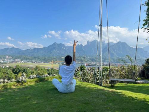 a woman sitting on the grass on a swing at 张家界东篱山居民宿- Free pick up service in Zhangjiajie