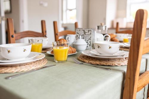 einen Tisch mit Teller und Tassen Orangensaft in der Unterkunft Serenity House, Whitehall Ballycastle in Ballycastle