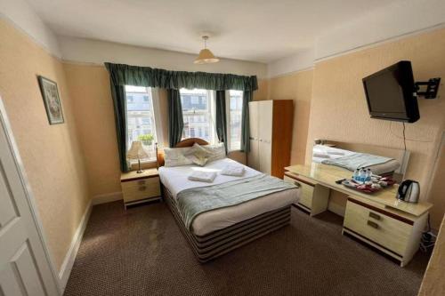 a bedroom with a bed and a desk and a television at Belvedere Guest House, Great Yarmouth in Great Yarmouth