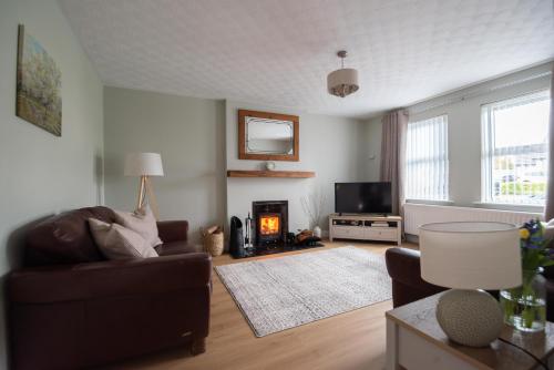 a living room with a couch and a fireplace at Serenity House, Whitehall Ballycastle in Ballycastle