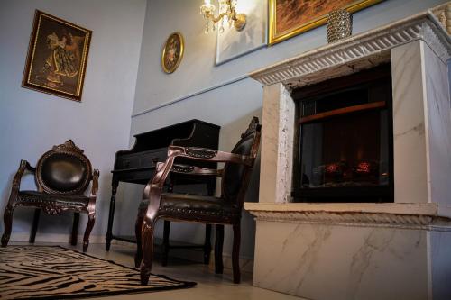 a living room with two chairs and a fireplace at Rincón Aranzazú Breakfast & Terrace in San Luis Potosí