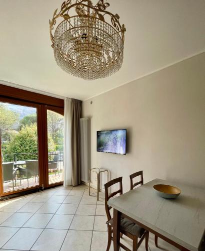 a dining room with a table and a chandelier at Residence Villa Margherita WITH POOL & HYDROMASSAGE in Cannobio