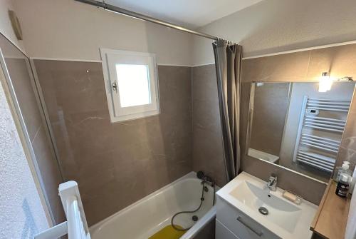 une salle de bain avec un lavabo et une baignoire et un lavabo dans l'établissement Bedroom Apartment in Le Lavandou Pool Parking, au Lavandou