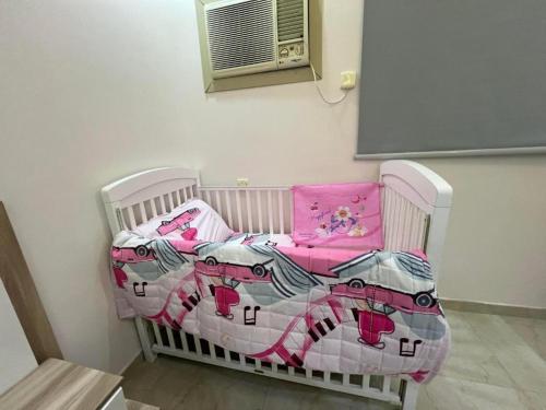 a white crib with a pink blanket on it at الوسام شقة كبيرة 3 غرف نوم وصالة Large apartment with 3 bedrooms and a living room in Taif