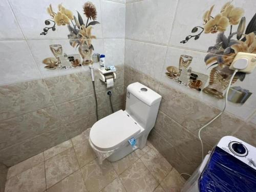 a bathroom with a toilet and flowers on the wall at الوسام شقة كبيرة 3 غرف نوم وصالة Large apartment with 3 bedrooms and a living room in Taif