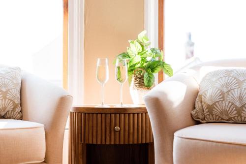 two glasses of wine on a table next to two chairs at Fairview House in Sheringham