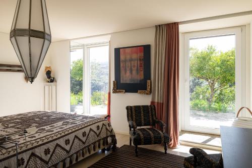a bedroom with a bed and a chair and windows at Belavista Villages in Riba Douro