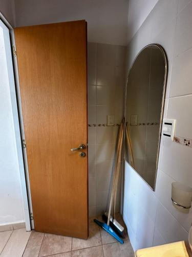 ein Badezimmer mit einer Holztür und einem Spiegel in der Unterkunft Monoambiente en Costanera Posadas Misiones in Posadas