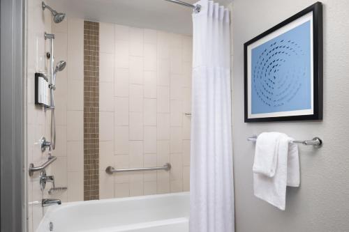 a bathroom with a tub and a shower with a shower curtain at Hyatt Place Atlanta Airport North in Atlanta