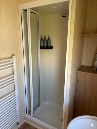 a bathroom with a shower stall with three bottles at 15 Maple Rise in Gristhorpe