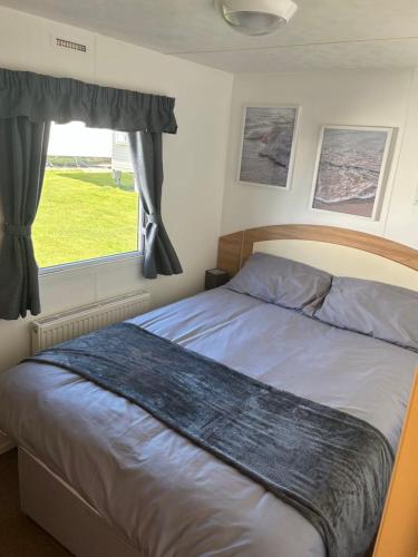 a bedroom with a large bed with a window at 15 Maple Rise in Gristhorpe