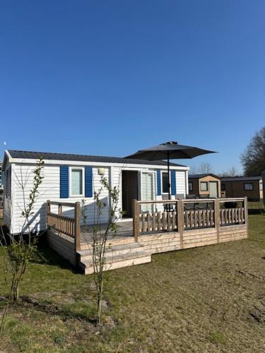 a house with a wooden deck with an umbrella at Figaro - Gasselte, Drenthe, 4 persoons, airco in Gasselte