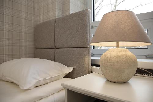 a lamp sitting on a table next to a bed at Apartament w Sosnowym SPA in Serock