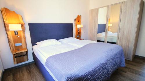 a bedroom with a large bed and a mirror at Komfort Hotel Am Kurpark in Bad Homburg vor der Höhe