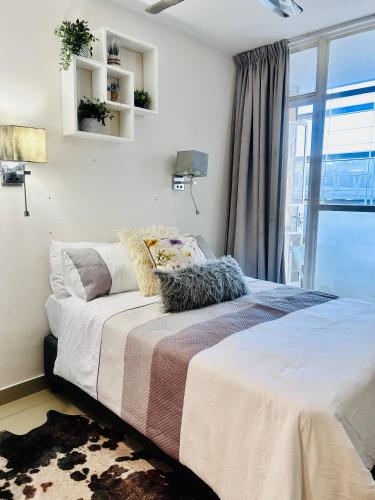 een slaapkamer met een bed en een groot raam bij 47 on Hyde Park in Kaapstad