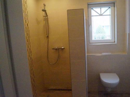 baño con ducha, aseo y ventana en Holiday apartment Utholm, en Tönning