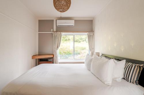 a bedroom with a white bed with a window at Togari Inn Suites in Iiyama